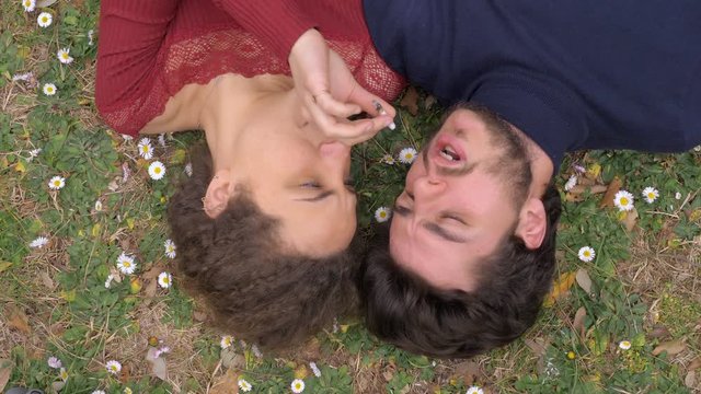 relaxed young lovers smoking joint lying on meadow in the park