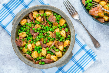 Potato gnocchi with green peas, pesto, proscuitto and chorizo in a bowl - overhead view
