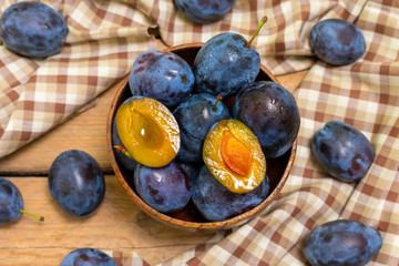 Ripe juicy plums in a wooden bowl. Juicy fruits on a wooden background. Country style.