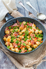 Potato gnocchi with green peas, pesto, proscuitto and chorizo in frying pan