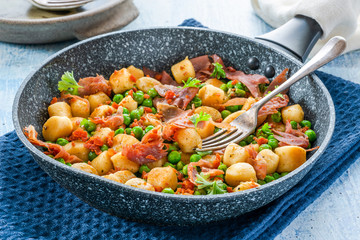 Potato gnocchi with green peas, pesto, proscuitto and chorizo in frying pan