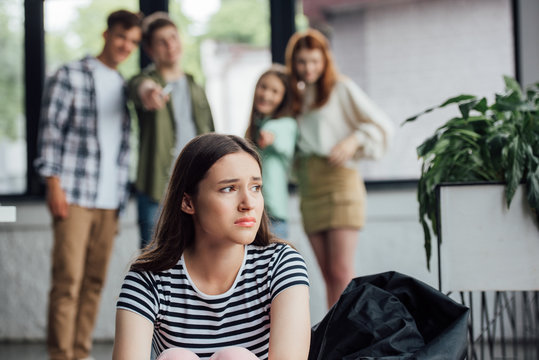 Selective Focus Of Group Of Teenagers Bullying Sad Girl In School