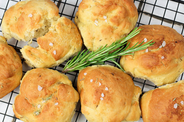 homemade fresh herb bread rolls of Provencal herbs with salt and a sprig banch of rosemary. Bread rolls bakery style on the cooling wrak