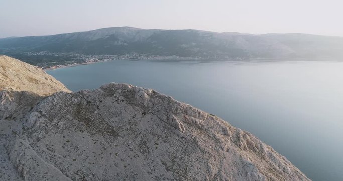 Aerial Drone flight in summer over mountains on the island krk near baska in croatia during sunrise over the sea