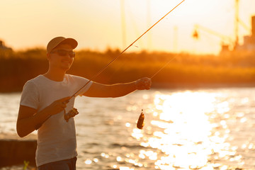 happy young fisherman with sea goby fish at sunset. soft light