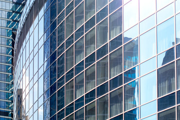 Plakat Modern office building with sky reflection on Windows against blue cloudy sky.