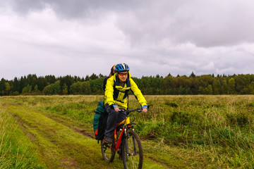 cyclist hiker rides on a dirt road through a field