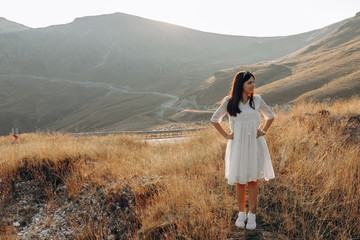 Naklejka premium stylish traveler girl in hat with backpack jumping in mountains. happy hipster woman having fun on top of mountain. space for text. wanderlust and travel concept. atmospheric moment