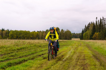 cyclist hiker rides on a dirt road through a field