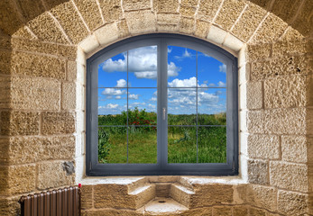 Fragment of a stone wall with a window. Summer landscape outside the window