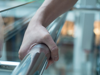 man holding a hand rail in mall closeup