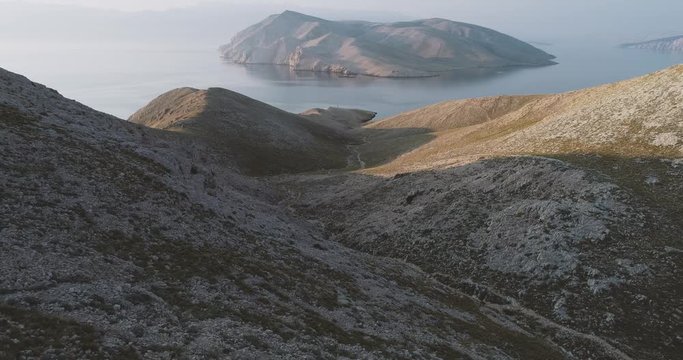 Aerial Drone flight in summer over mountains on the island krk near baska in croatia during sunrise over the sea