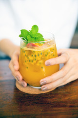 passion fruit juice iced in a glass iced no caffeine. Put on wooden table in cafe Copy space concept. Hand hold the glass.