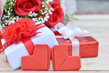 Red roses bouquet, gift box and red hearts shape on wooden background.
