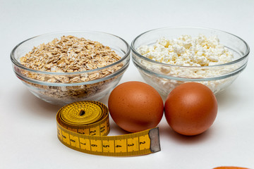 cereals, measuring tape, farm cottage cheese, egg close up on white background protein healthy diet fat free concept eco product sports nutrition