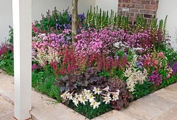 A full and colourful mixed flower border in a patio of a contemporary garden