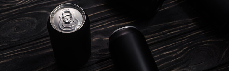 panoramic shot of black cans of beer on wooden table with copy space