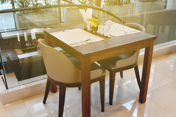 Modern interior of restaurant. Wooden furniture design and empty tables set ready for dinner.