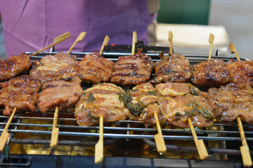 Pork mix with seasoning/sauce and small wood skewer grilled on grill.