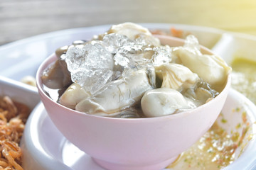 Raw fresh oysters with sauce is delicious and covered ice on white cup.