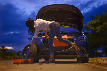 Woman try to fix problem of car by herself with belonging tools, need help and assistant at dark of the night, scary and worry alone in the dark, car engine failure or tire need replacement