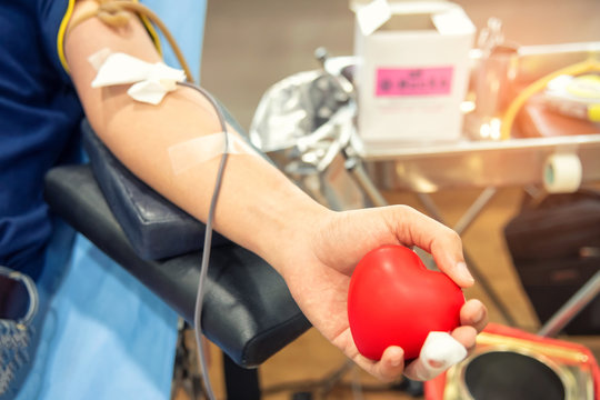 Blood donor at donation, transfusion. Closeup blood donor squeezes the bouncy ball in the form of heart in his hand. Healthcare and charity. Concept image for World blood donor day-June 14.