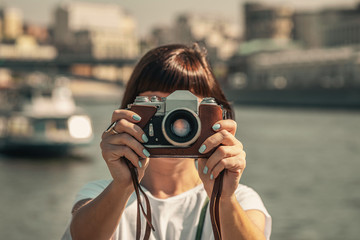 Woman holding retro vintage camera outdoors. Old camera. Female photography.