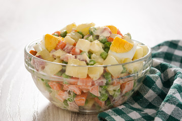 Traditional Russian salad for Christmas. Olivier salad on wooden table