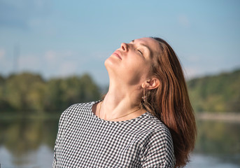 a middle-aged woman in a plaid tunic stands on the riverbank