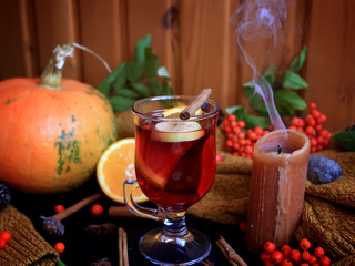 Autumn mulled wine based on red wine with orange, apple and spicy cinnamon sticks, and star anise on a black background. Traditional autumn drink on a background of leaves. 