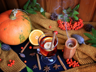 Autumn mulled wine based on red wine with orange, apple and spicy cinnamon sticks, and star anise on a black background. Traditional autumn drink on a background of leaves. 
