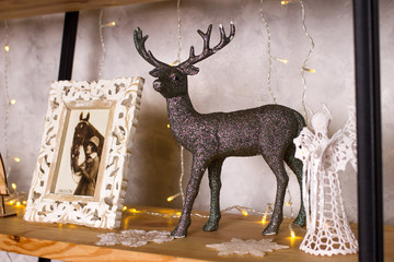 Decoration of the apartment for Christmas and New Year: shiny deer, photo frame, angel.