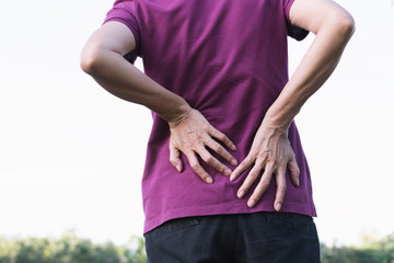 Closeup hands of woman touching her back pain in healthy concept on nature background.