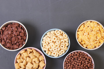 Different types of breakfast cereals on a colored background top view.