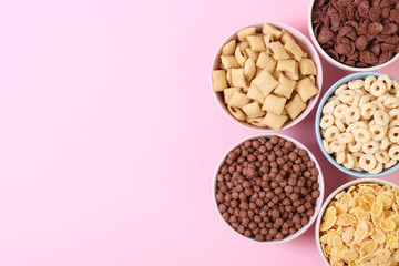Different types of breakfast cereals on a colored background top view.
