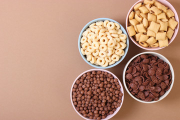 Different types of breakfast cereals on a colored background top view.