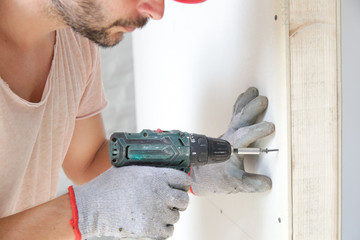 Handyman drilling screws into plasterboard with an electric screwdriver, home improvement concept