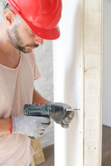 Handyman drilling screws into plasterboard with an electric screwdriver, home improvement concept