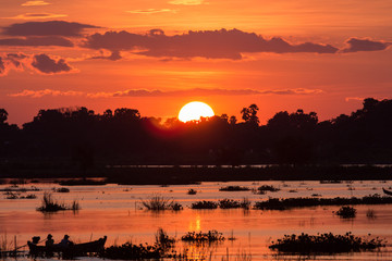 Fototapeta premium Silhouette of fisherman to drive a boat on the lake at sunset scene in Mandalay, Myanmar