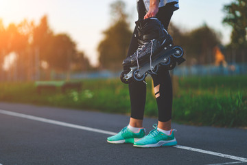 Teenager holds roller skates for inline skating outdoors.