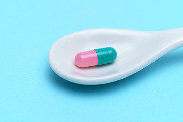 Spoon with tablet on blue background. Pharmacy, medicine concept. Taking medications and pills. Vitamins and minerals for health