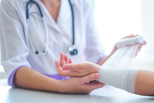 Doctor is bandaging wrist of patient in hospital