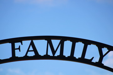 Black metal family sign on blue sky background
