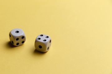 White gaming dice on yellow background. Top view. Flat lay. Copy space. Game of chance concept. Close-up. Pastel colors