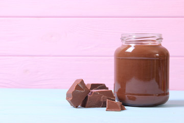 chocolate paste in a glass jar on a colored background. Chocolate butter, chocolate sauce.