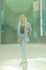 Outdoors lifestyle fashion portrait of happy stunning blonde girl. Beautiful smile. Walking to the city street. Long light hair. Joyful and cheerful woman. Happiness.