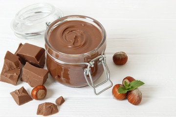 chocolate paste in a glass jar on a colored background. Chocolate butter, chocolate sauce.