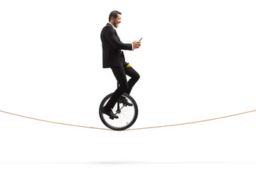 Happy businessman riding a unicycle on a rope and holding a mobile phone © Ljupco Smokovski