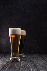 glasses of fresh light and dark beer on wooden table