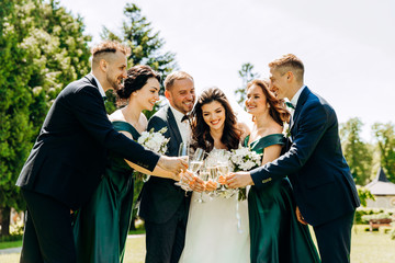 Happy newlyweds with friends hold glasses in hands